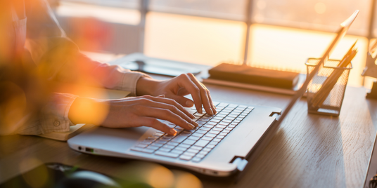 Person erstellt eine Webseite am Laptop im Büro