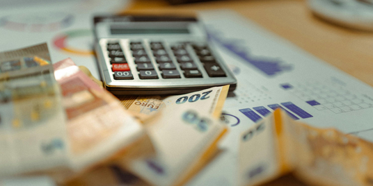 Taschenrechner und Geldscheine als Symbol für faire Preise