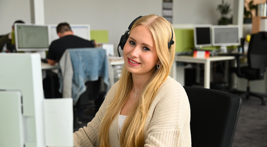pikster Kundenservice mit Headset im Büro für Deine Unterstützung bei SHK-Bestellungen
